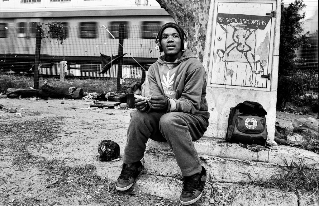 Teenager rolling a cigarette from a piece of newspaper, Claremont, 2013.