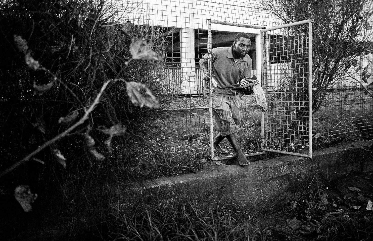 Person crossing railway tracks with shoes in his hand, Claremont, 2013.