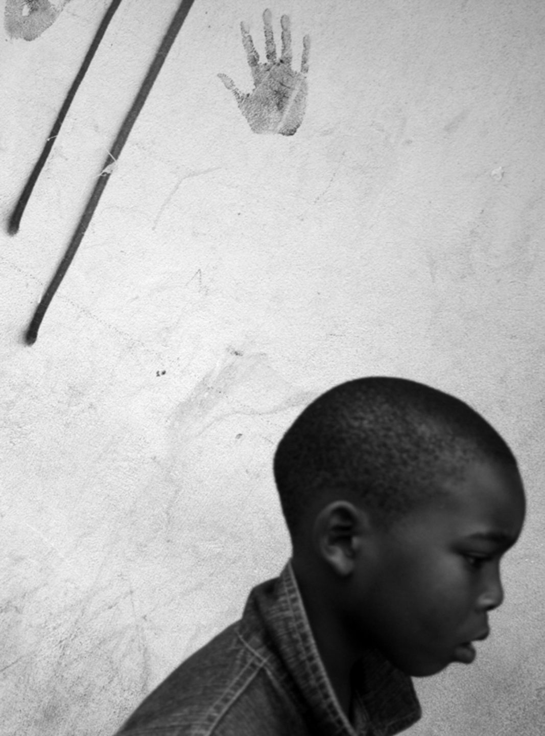 Boy walks past the mark of a hand printed on wall, 2012.